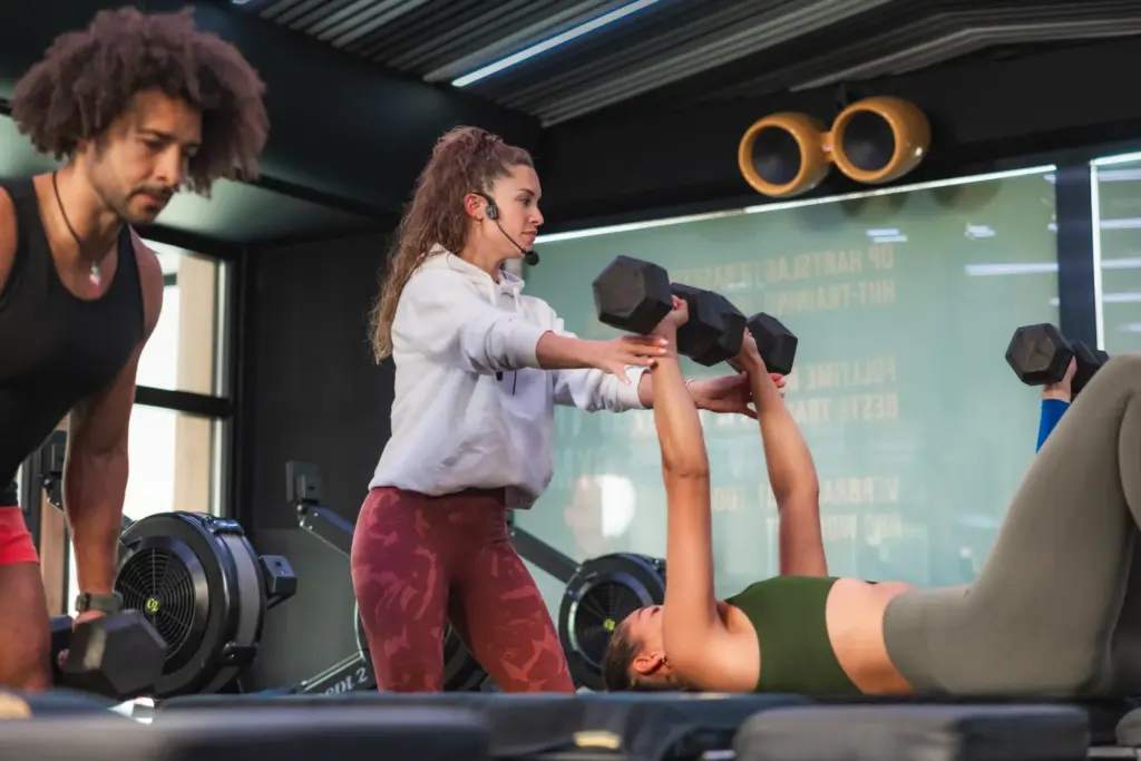 Trainer begeleidt een sporter bij een krachtoefening met dumbbells